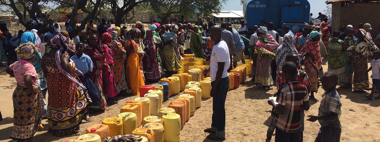 Water brought from a truck to fill buckets and donated water cistern for villagers