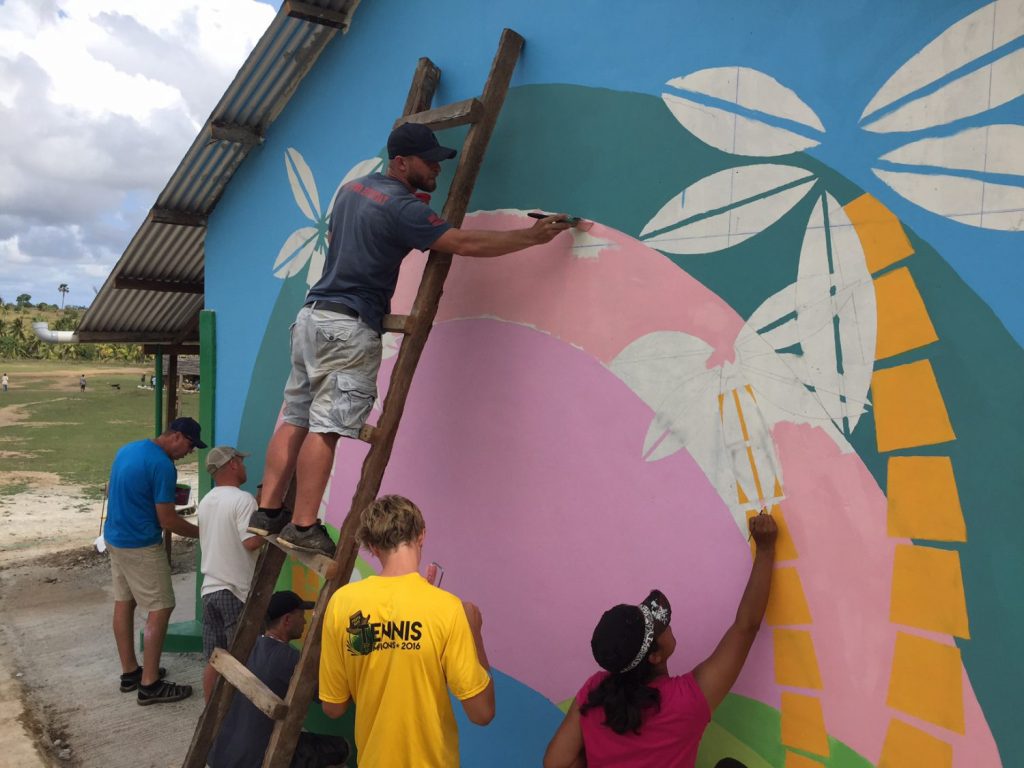 Non-profit volunteers painting a mural on the side of a school in Kenya