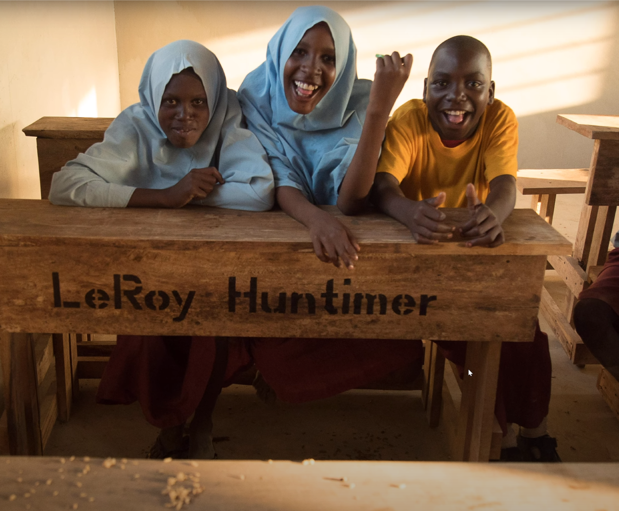 African students at desk presented to their village